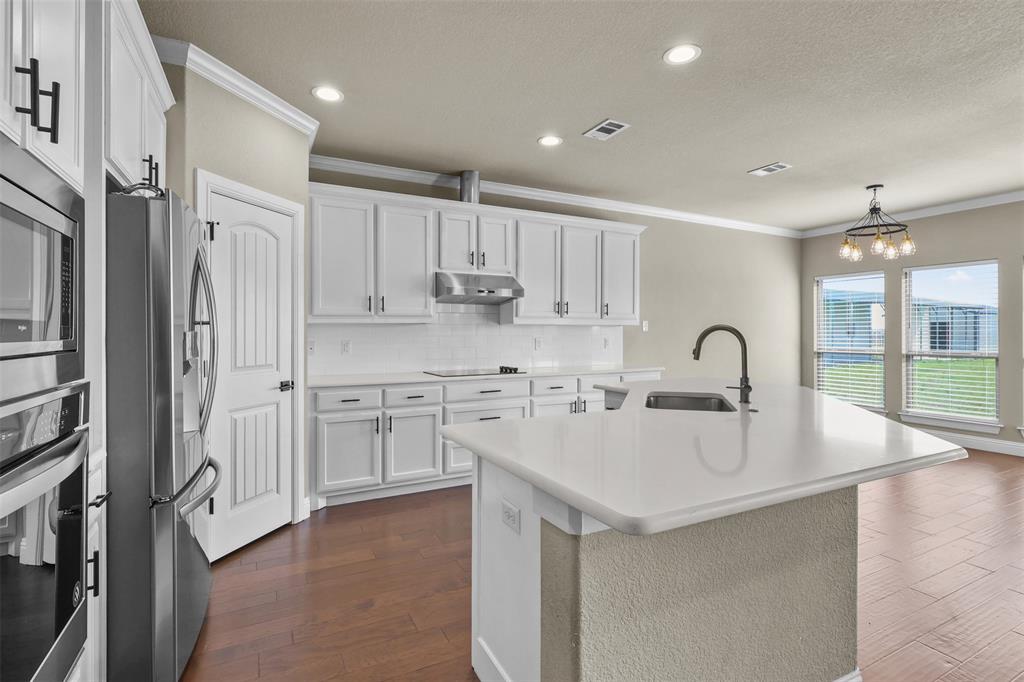 2451 Neck Road Palmer, TX 75152 - Photo 11 of 32 a large kitchen with kitchen island a sink a stove a refrigerator and white cabinets