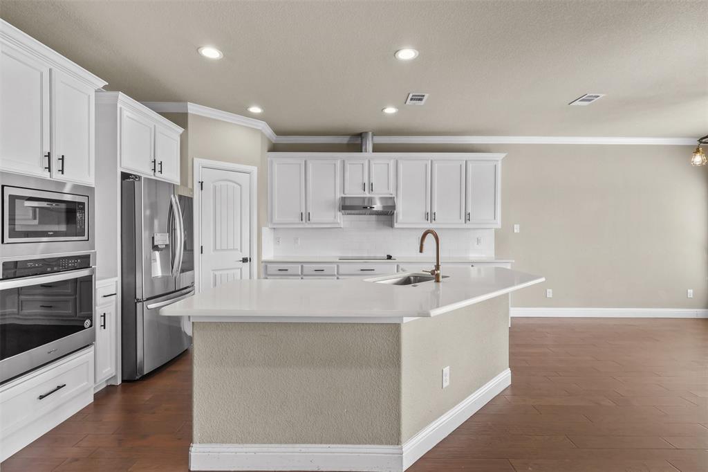 2451 Neck Road Palmer, TX 75152 - Photo 12 of 32 a kitchen with kitchen island white cabinets and stainless steel appliances
