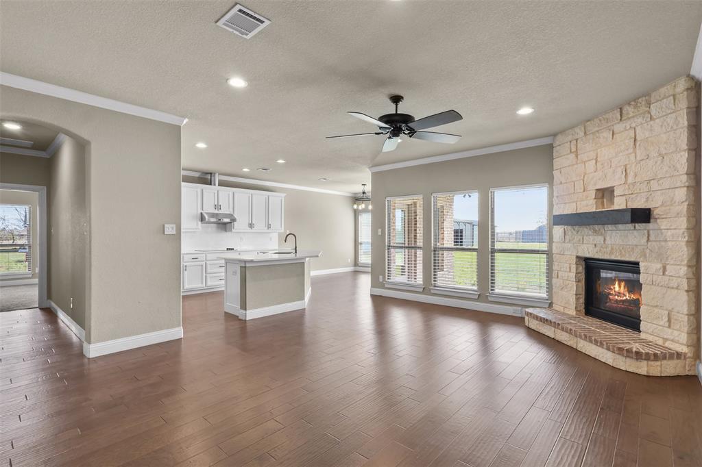 2451 Neck Road Palmer, TX 75152 - Photo 10 of 32 a view of an empty room with wooden floor and a kitchen