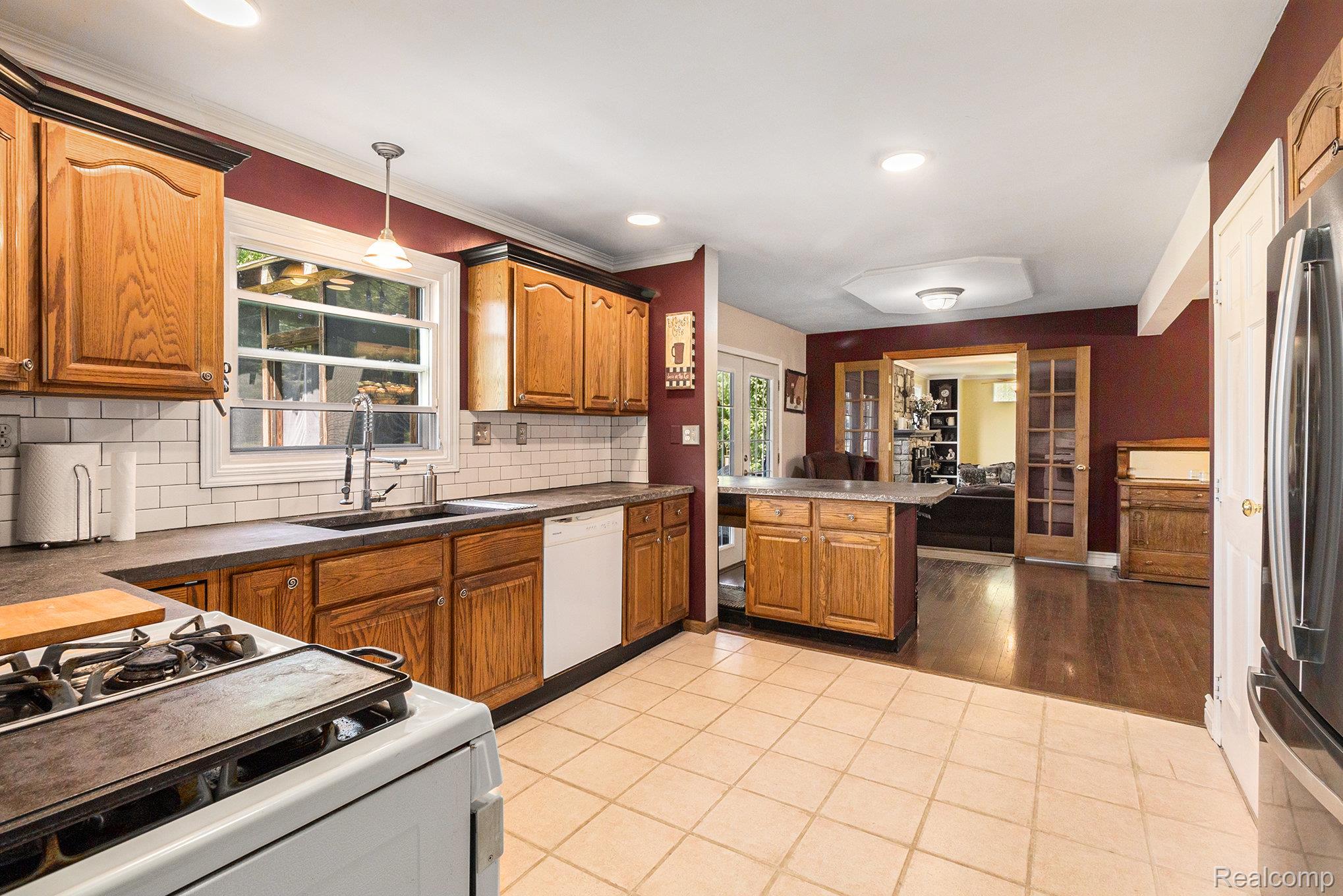 5083 Curtis Road Attica, MI 48412 - Photo 8 of 44 Kitchen with wood finish cabinets, white appliances, light tile patterned floors, and decorative light fixtures