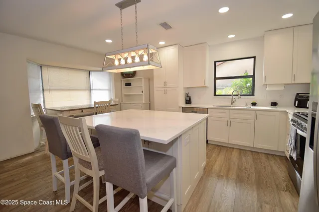 a kitchen with kitchen island a wooden floor and white appliances