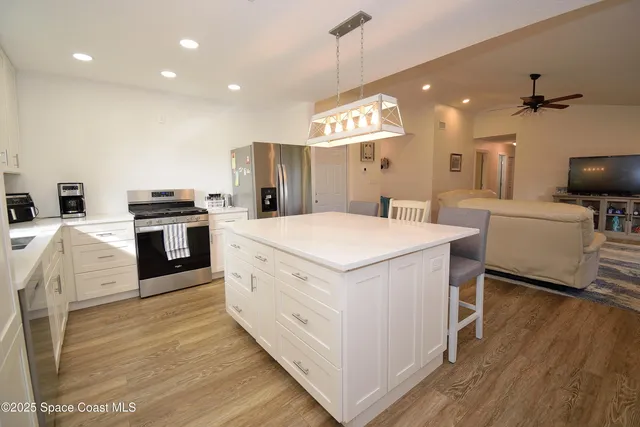 a large kitchen with kitchen island a stove a sink a center island and a wooden floor