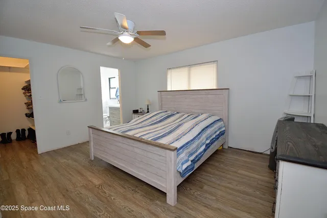 a bedroom with a bed and a dresser with wooden floor