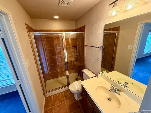 a bathroom with a sink a toilet a mirror and shower