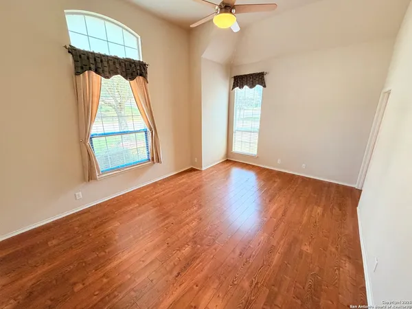 an empty room with wooden floor and windows