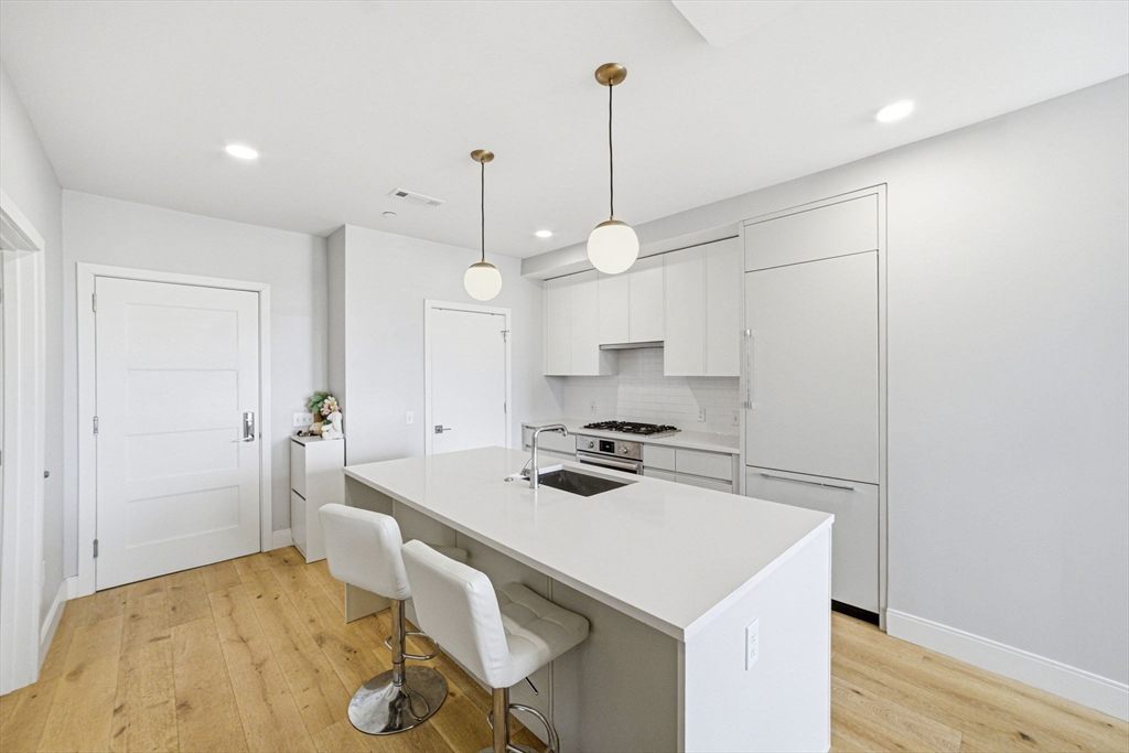 191 Washington Street, Unit 413 Boston, MA 02135 - Photo 26 of 40 a kitchen with a stove a refrigerator a sink and chairs