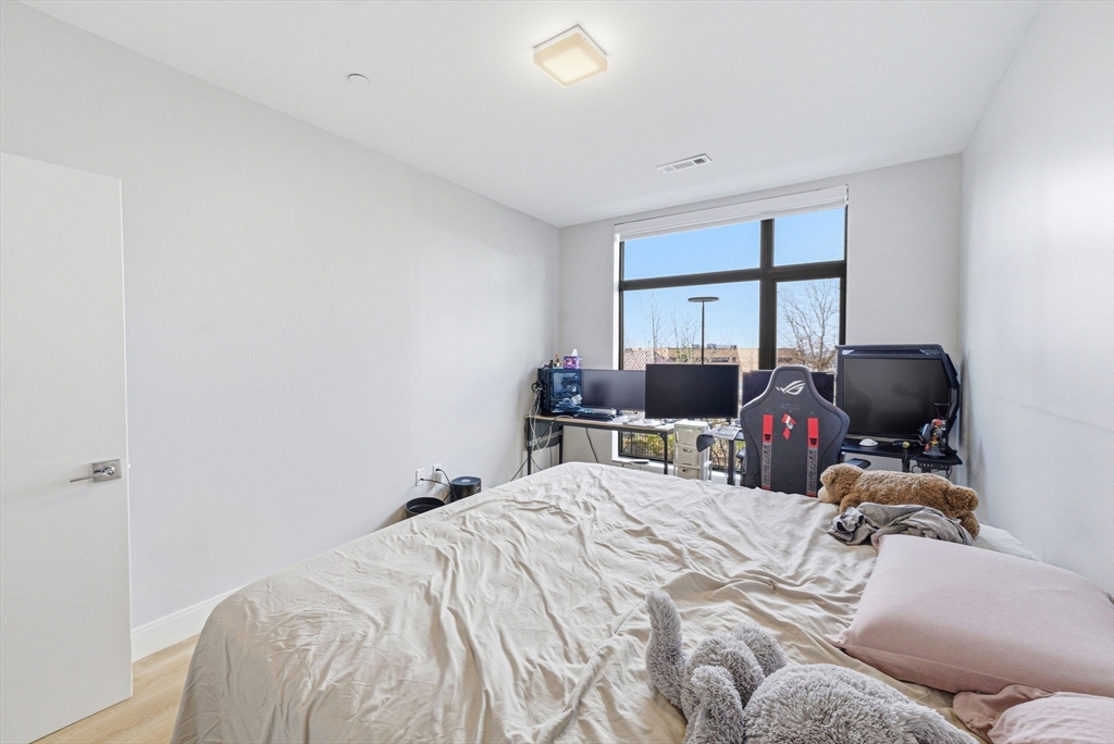 191 Washington Street, Unit 413 Boston, MA 02135 - Photo 29 of 40 a bedroom with a bed and a large window