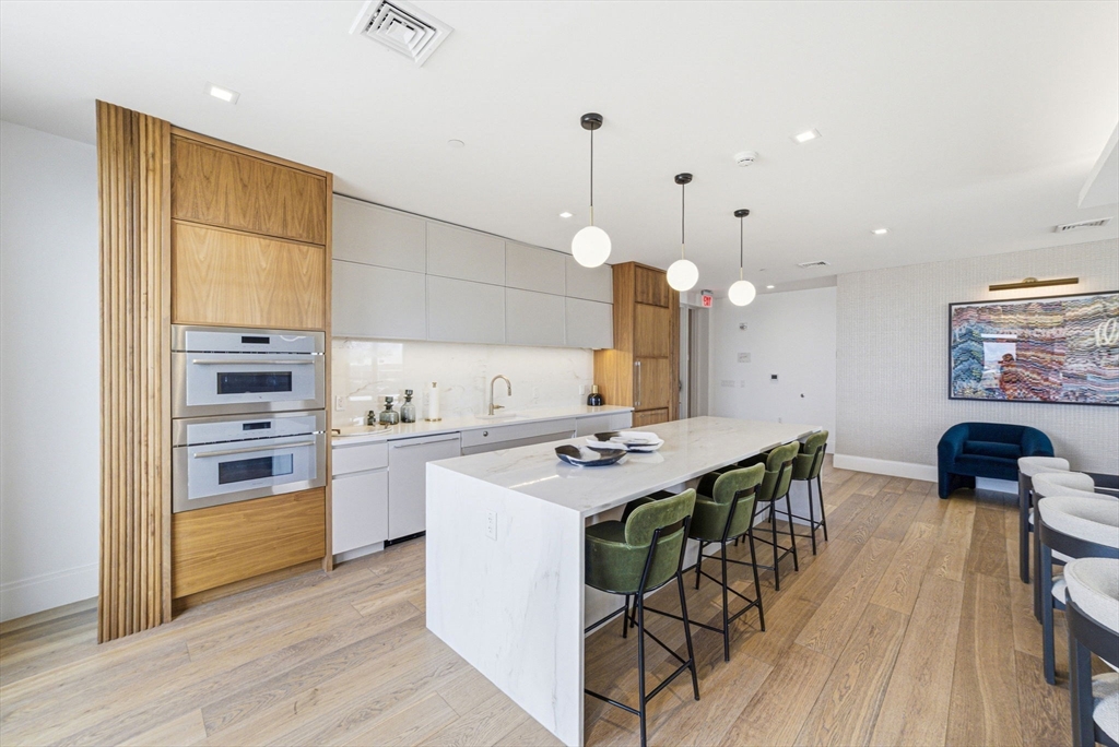 191 Washington Street, Unit 413 Boston, MA 02135 - Photo 35 of 40 a kitchen with a table chairs stove and wooden floor