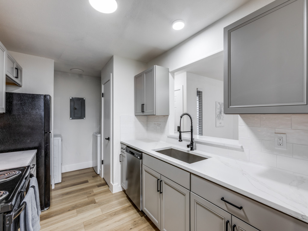 1845 River Crossing Circle, Unit A Austin, TX 78741 - Photo 16 of 31 Kitchen with gray cabinets, light wood finished floors, backsplash, and stainless steel dishwasher