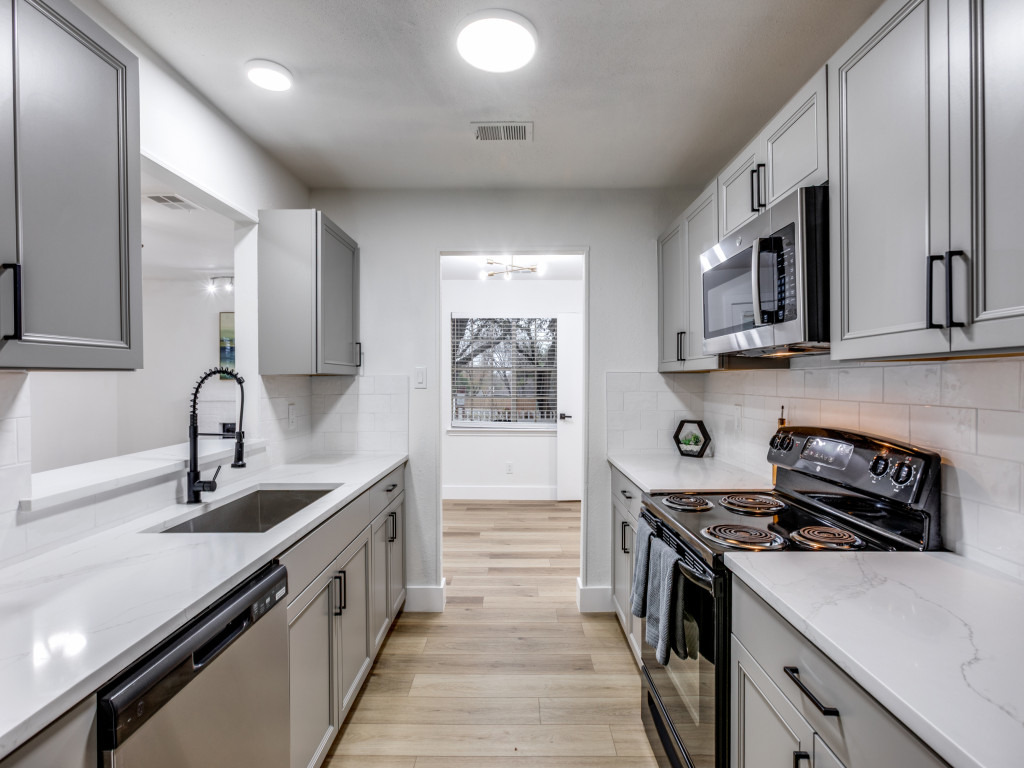 1845 River Crossing Circle, Unit A Austin, TX 78741 - Photo 17 of 31 Kitchen with gray cabinetry, stainless steel appliances, light stone countertops, light wood finished floors, and tasteful backsplash