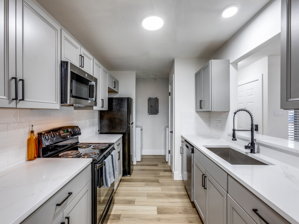 1845 River Crossing Circle, Unit A Austin, TX 78741 - Photo 6 of 31 Kitchen featuring gray cabinetry, appliances with stainless steel finishes, light stone countertops, light wood-type flooring, and tasteful backsplash