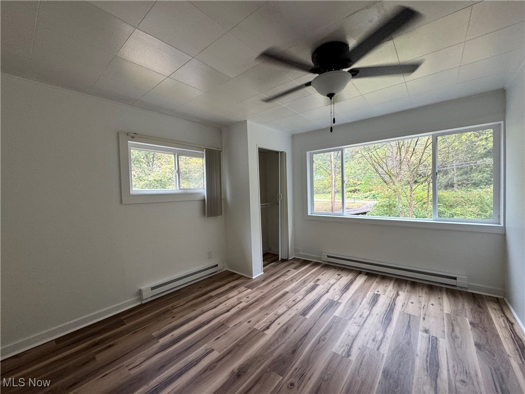 56068 Key Bellaire Road Bellaire, OH 43906 - Photo 8 of 25 Unfurnished bedroom with a baseboard heating unit, light wood-style floors, and a ceiling fan