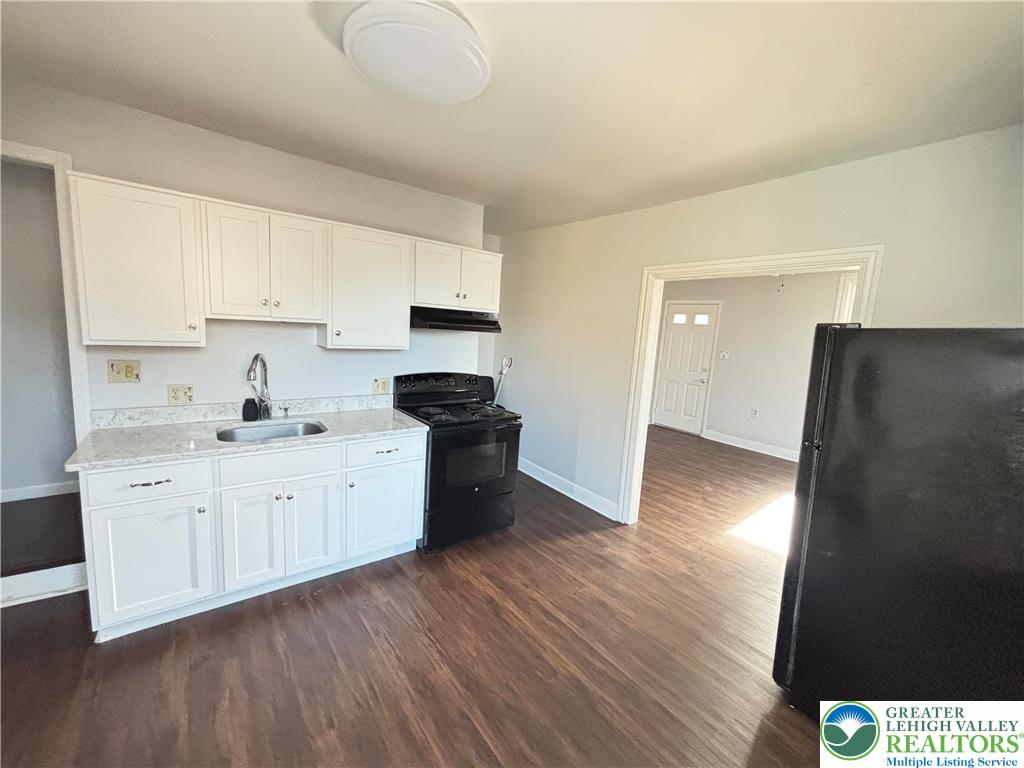 213 Penn Street Bath, PA 18014 - Photo 4 of 22 a kitchen with granite countertop a refrigerator a sink and white cabinets