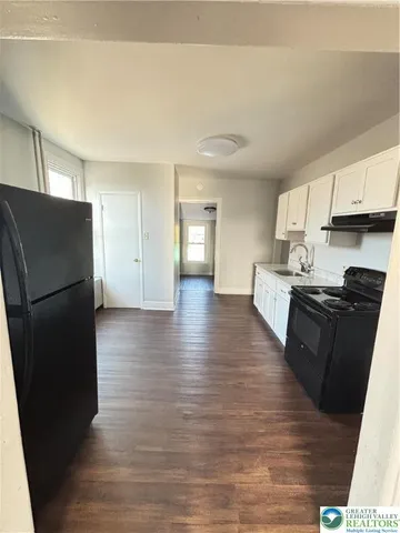 a kitchen with stainless steel appliances granite countertop a refrigerator a stove and a wooden floors