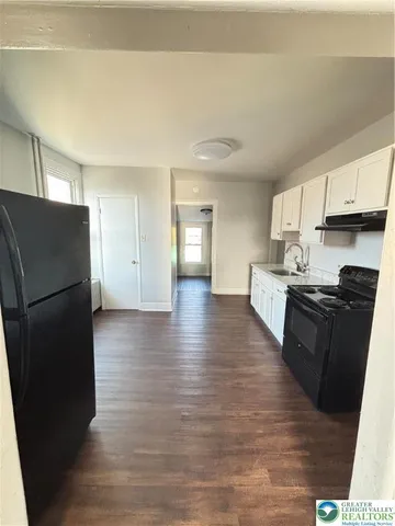 a kitchen with stainless steel appliances granite countertop a refrigerator a sink dishwasher and a stove with wooden floors