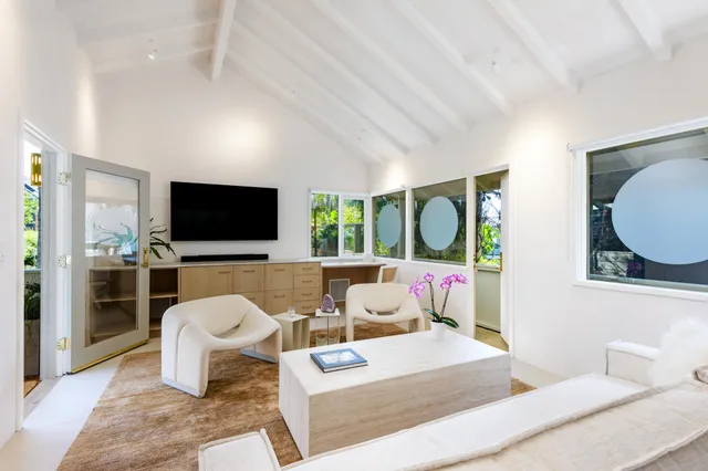 a living room with furniture a flat screen tv and a floor to ceiling window