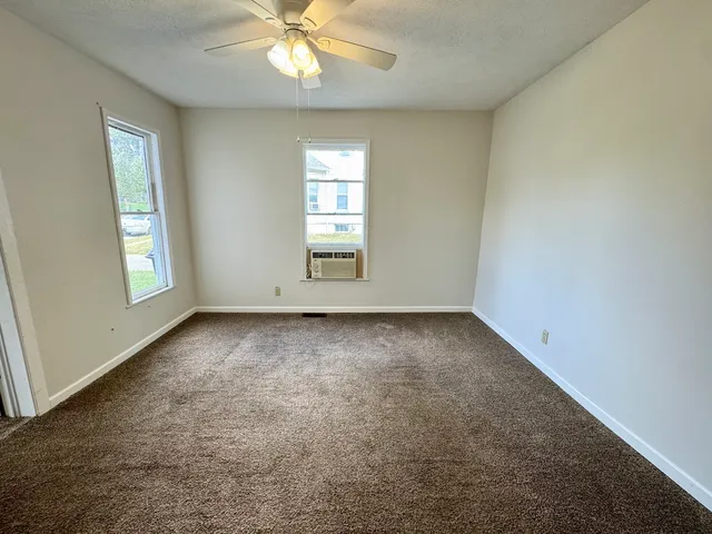 an empty room with windows and chandelier fan