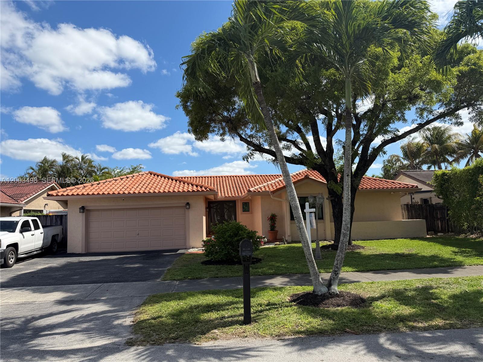 6010 Northwest 201st Lane Hialeah, FL 33015 - Photo 3 of 36 a front view of a house with a garden and trees