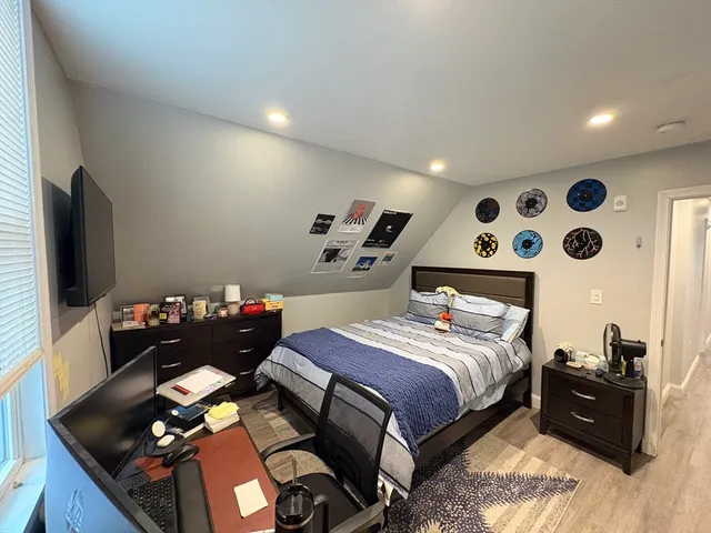 a bedroom with bed and a flat tv screen on dresser