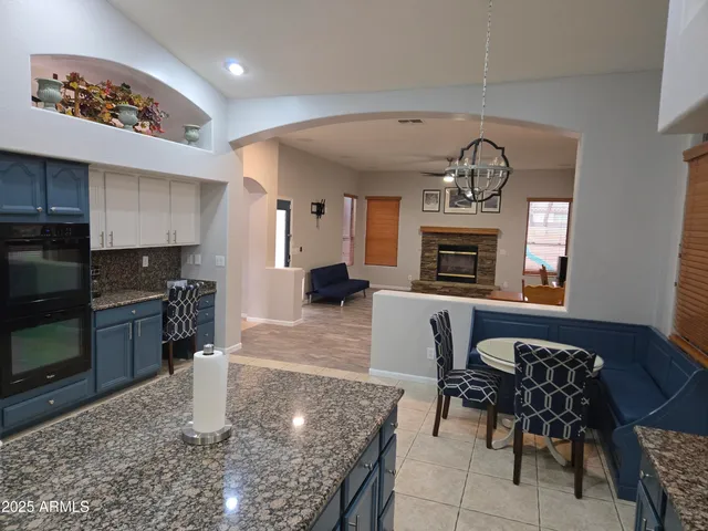 a kitchen with stainless steel appliances granite countertop a stove top oven a sink a dining table and chairs