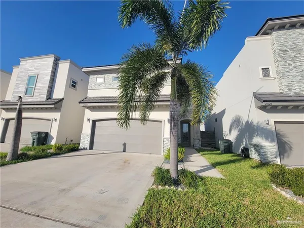 a view of a white house with a yard and palm trees