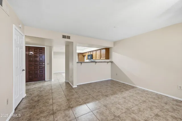 an empty room with kitchen and entrance