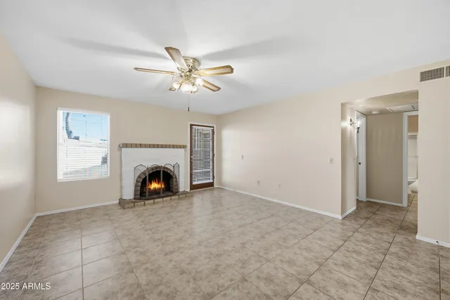 a view of a livingroom with a fireplace a ceiling fan and windows