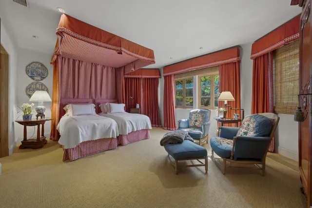 a spacious bedroom with a bed couches and a flat tv screen