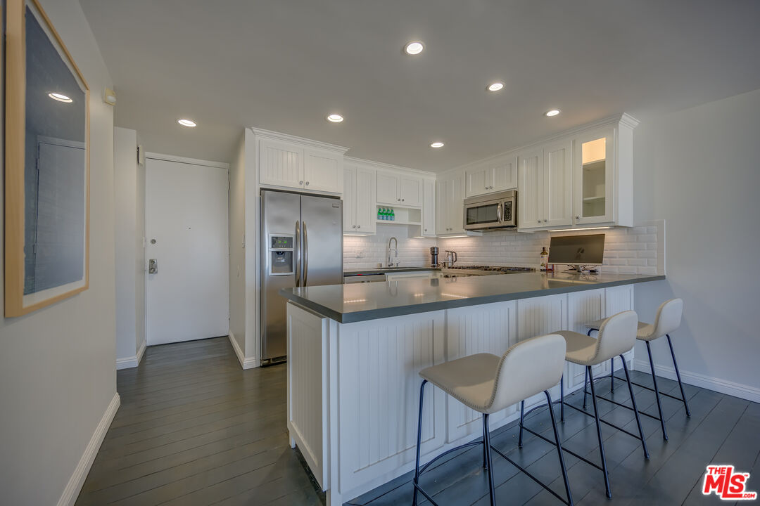 2 Ketch Street, Unit 107 Marina del Rey, CA 90292 - Photo 12 of 22 a kitchen with kitchen island granite countertop wooden cabinets and refrigerator
