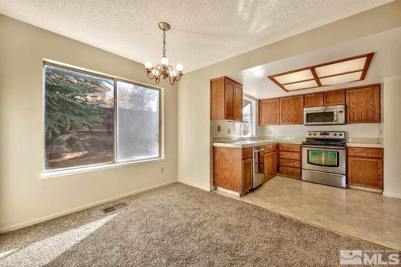 2702 Caballo Drive Reno, NV 89502 - Photo 8 of 17 a kitchen with stainless steel appliances granite countertop a stove top oven a sink dishwasher a refrigerator and a dining table with wooden floor