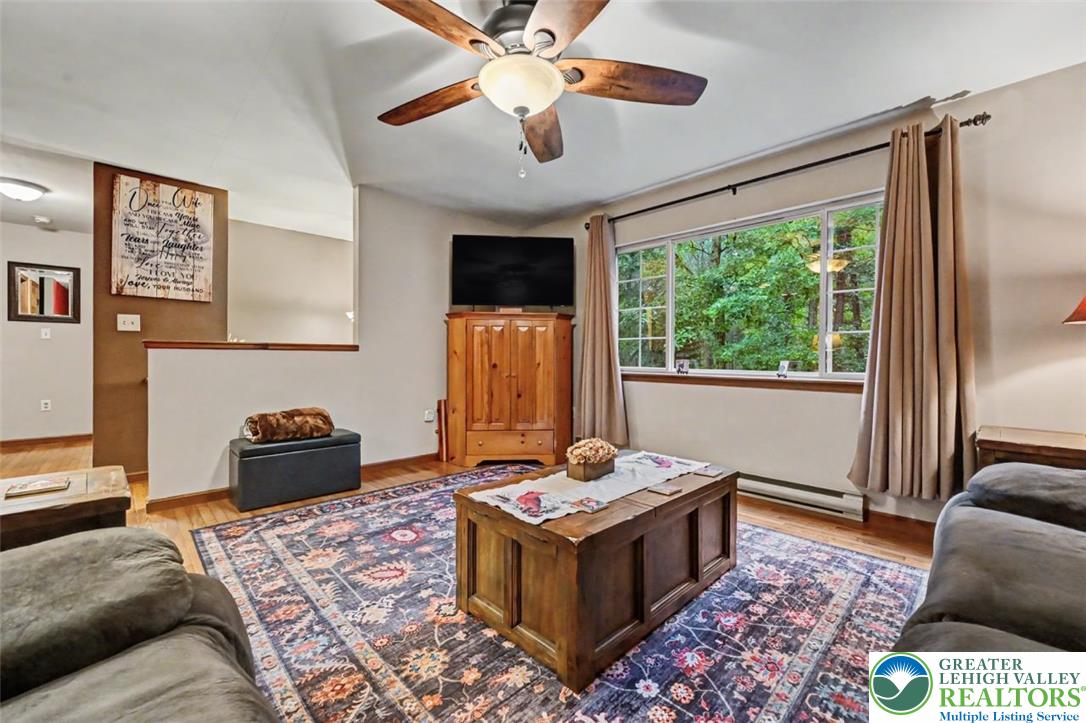 386 Upper Rdg Drive Effort, PA 18330 - Photo 17 of 56 A comfortable living space featuring polished hardwood floors and abundant natural light from a broad window overlooking lush trees.