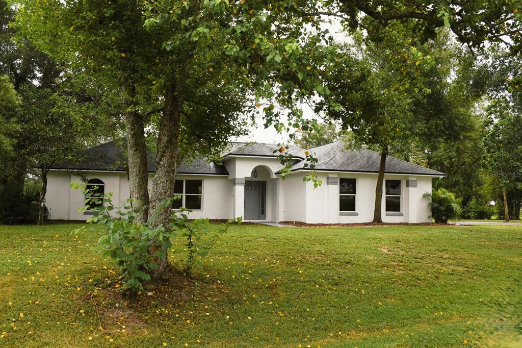 a white house with a small yard and large trees