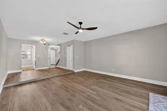 an empty room with wooden floor and ceiling fan