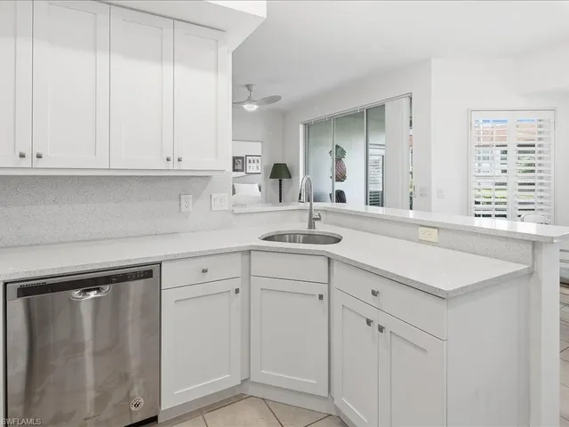 a kitchen with white cabinets and sink