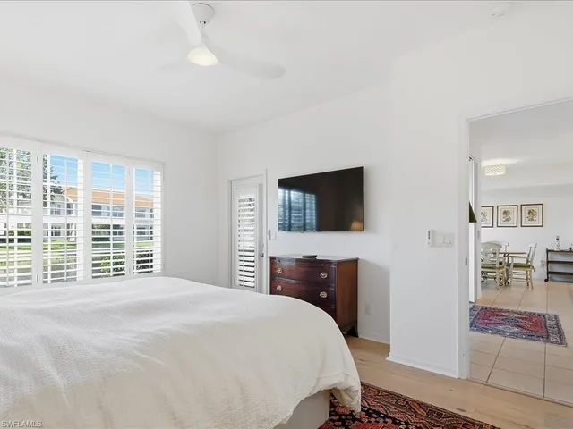 a bedroom with a large bed a flat tv screen and a dresser