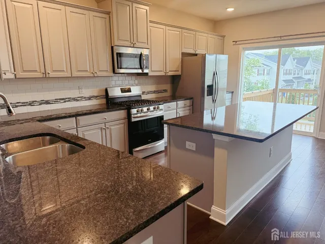 a kitchen with stainless steel appliances granite countertop a refrigerator a stove a sink and a microwave