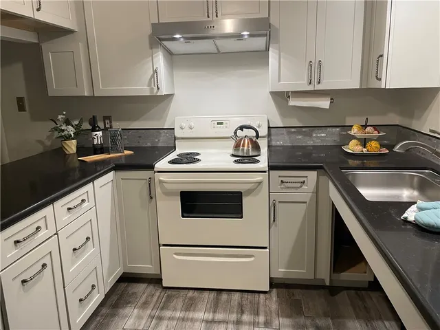 a kitchen with granite countertop white cabinets and white appliances