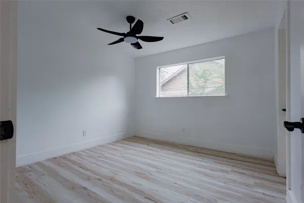 an empty room with wooden floor cabinet and windows