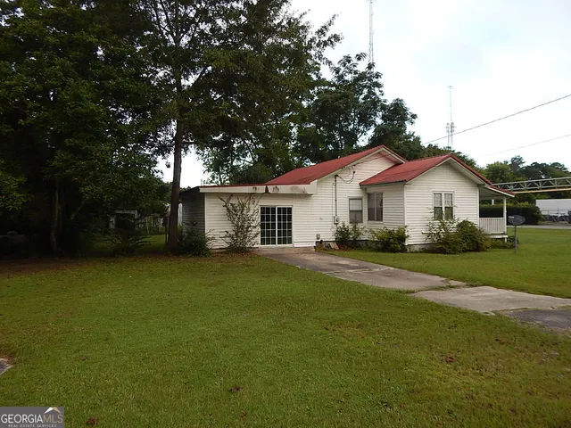 a view of a yard in front of a house with plants and large tree