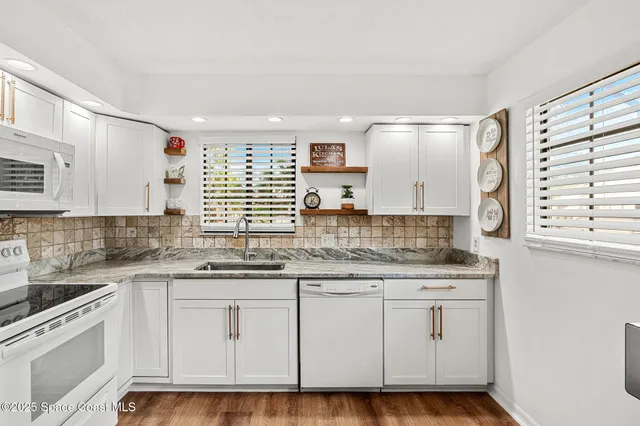 a kitchen with granite countertop white cabinets and white appliances