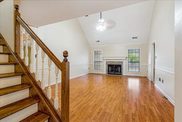 an empty room with wooden floor fireplace and windows