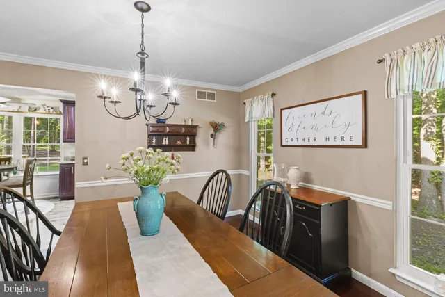 a view of a dining room with furniture a chandelier and large windows