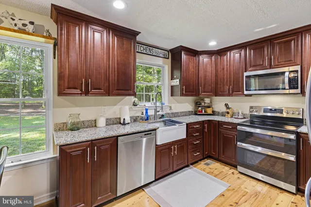 a kitchen with stainless steel appliances granite countertop wooden cabinets stove top oven and sink
