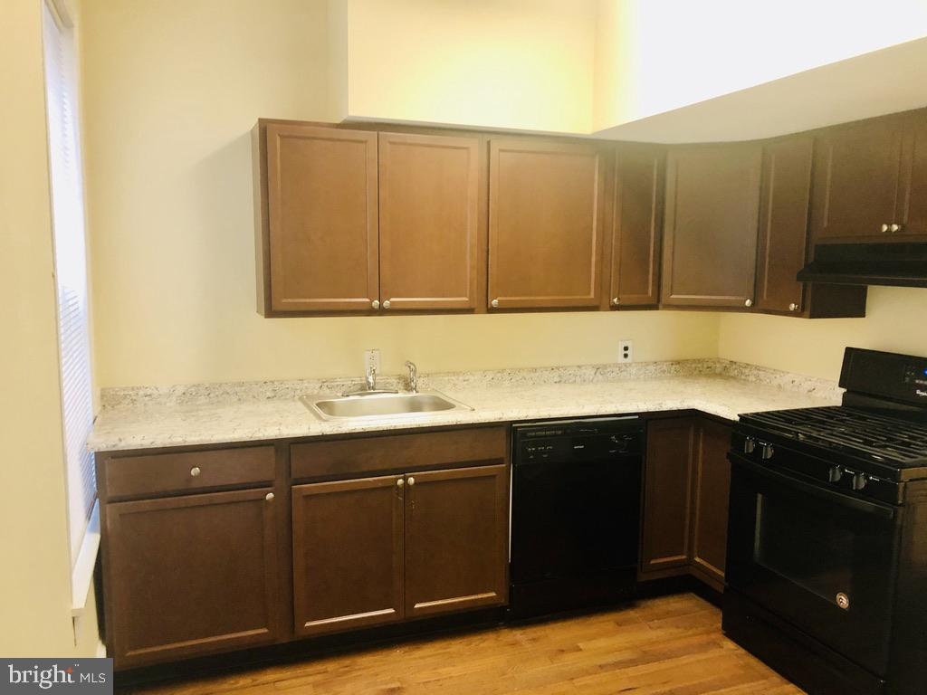 1415 North Harrison Street, Unit 2 Wilmington, DE 19806 - Photo 5 of 21 a kitchen with a sink cabinets and a stove top oven