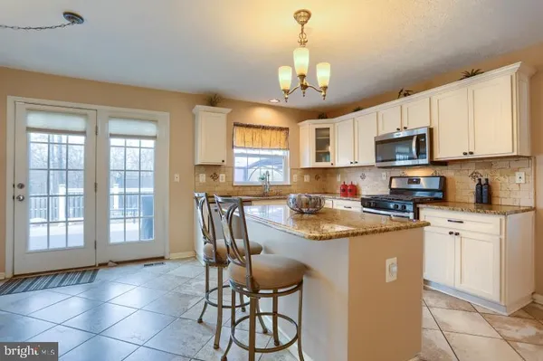a kitchen with stainless steel appliances granite countertop a stove top oven a sink a dining table and chairs