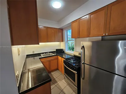 a kitchen with stainless steel appliances granite countertop a refrigerator a stove and a sink with wooden cabinets