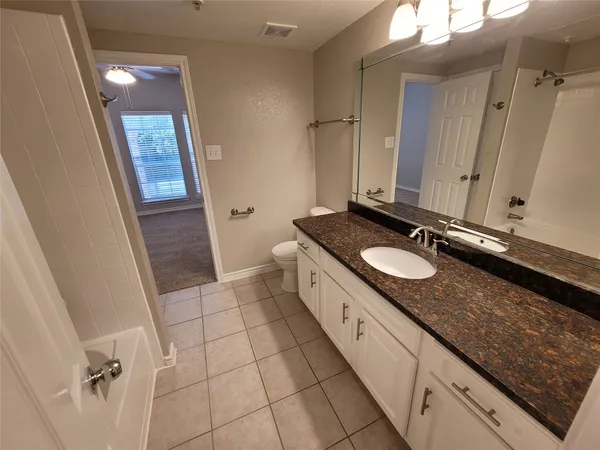 a spacious bathroom with a granite countertop sink and a mirror