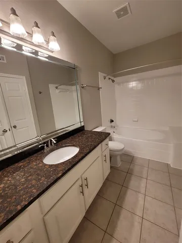 a bathroom with a granite countertop sink a toilet and a mirror