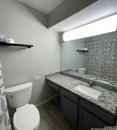 a bathroom with a granite countertop toilet sink and mirror