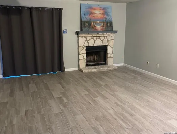 a view of an empty room with wooden floor and a fireplace